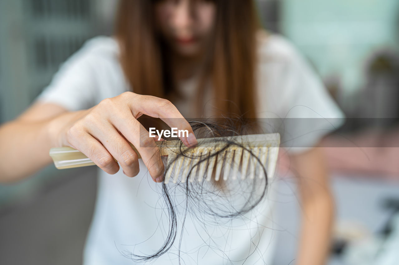 Asian woman have problem with long hair loss attach to comb brush.