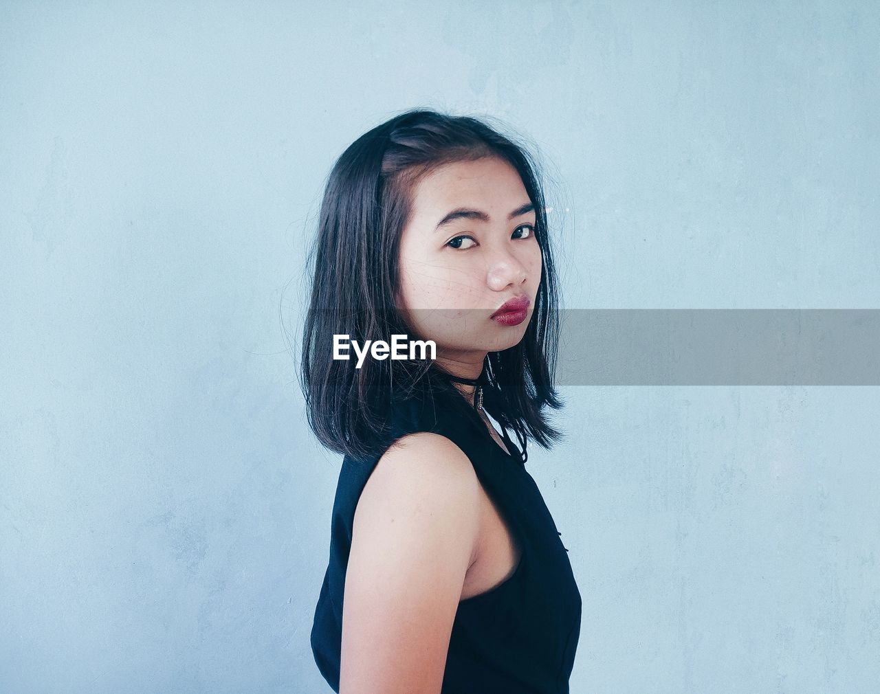 Portrait of young woman standing against wall