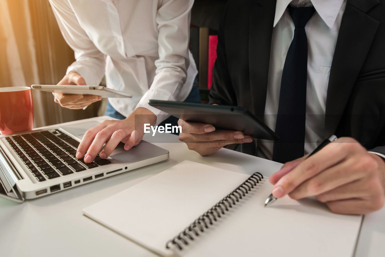 Midsection of business colleagues working on desk in office