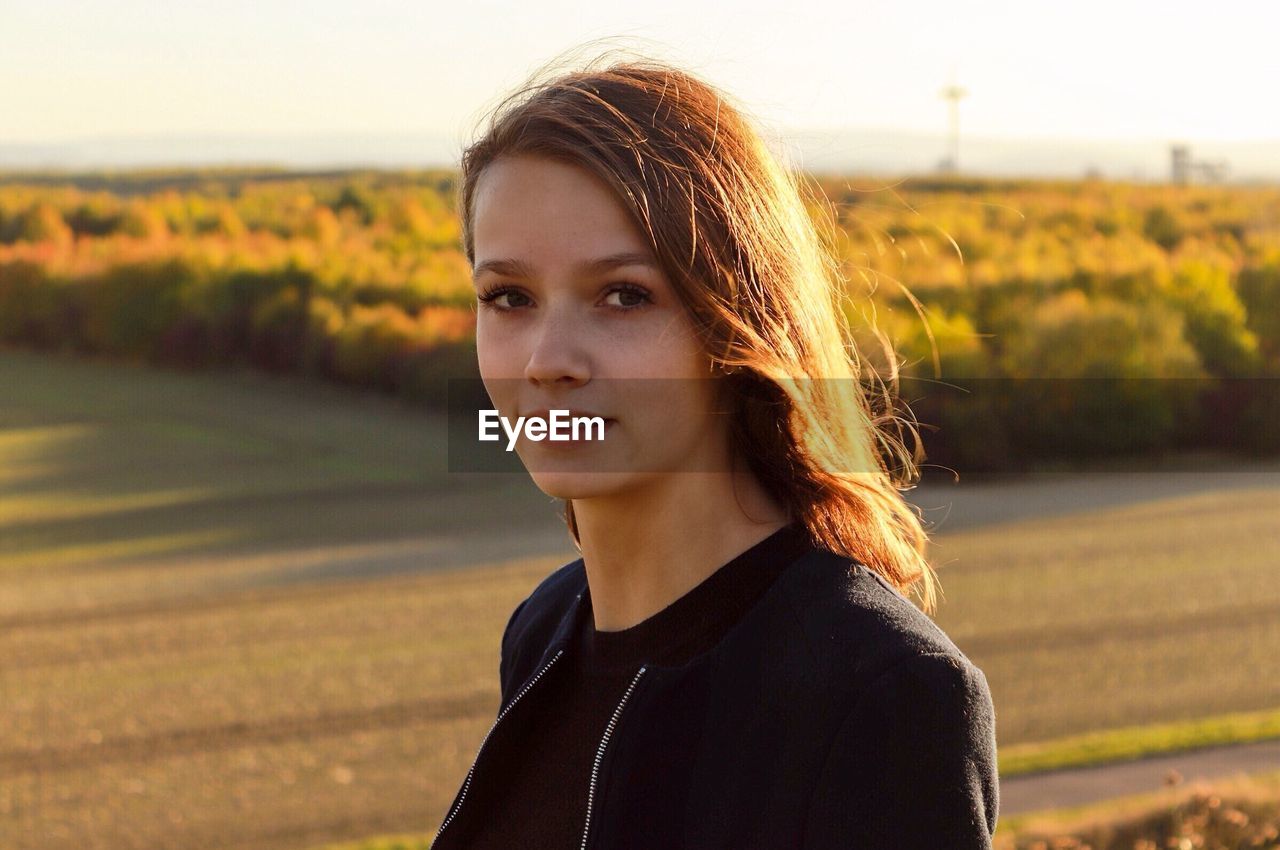 Portrait of young woman standing on field