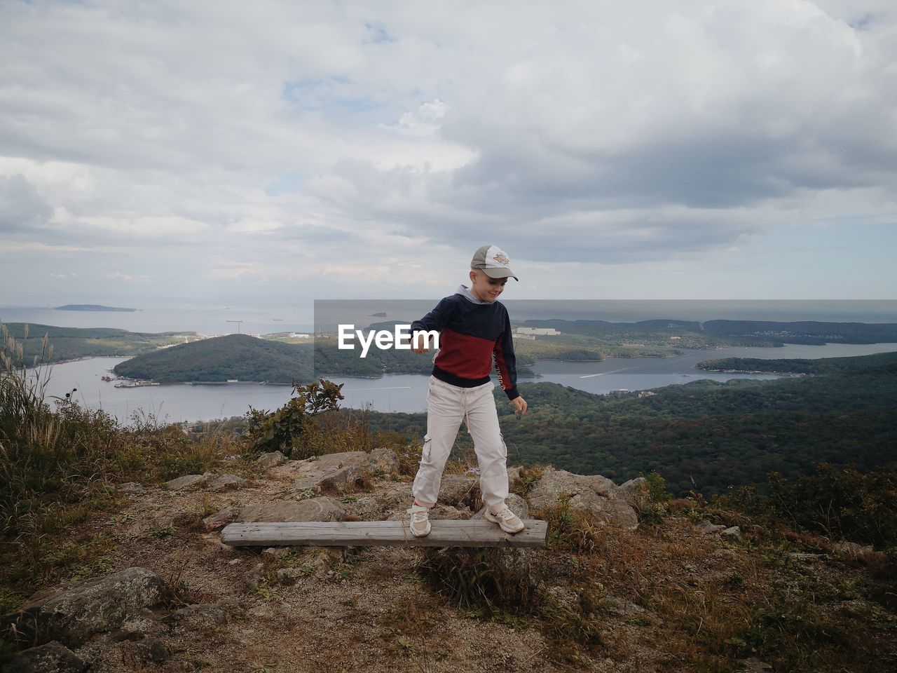 MAN STANDING ON MOUNTAIN LOOKING AT VIEW