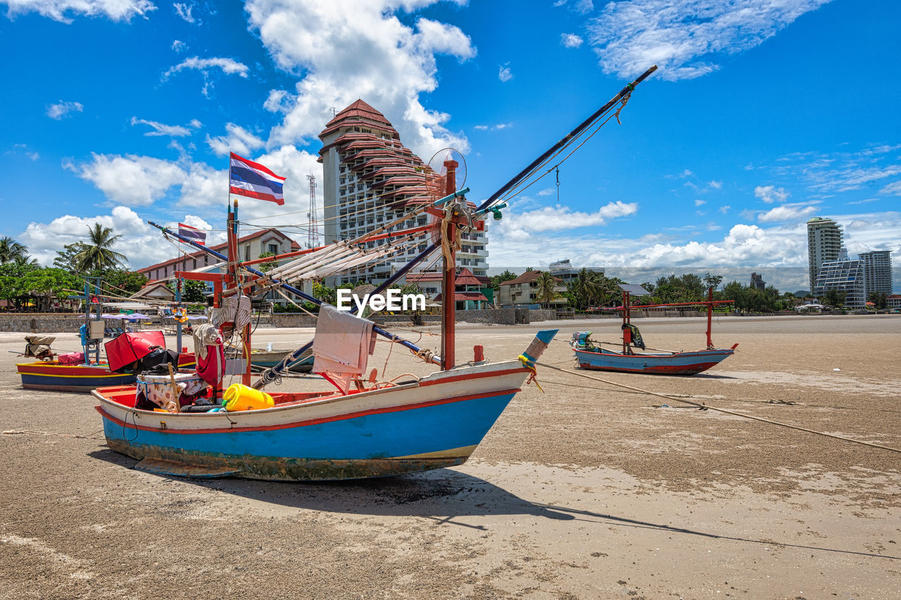 BOATS MOORED ON SHORE AGAINST SKY