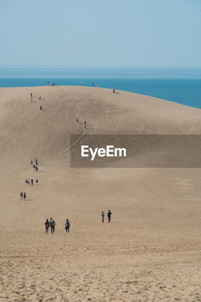 People on beach against clear sky