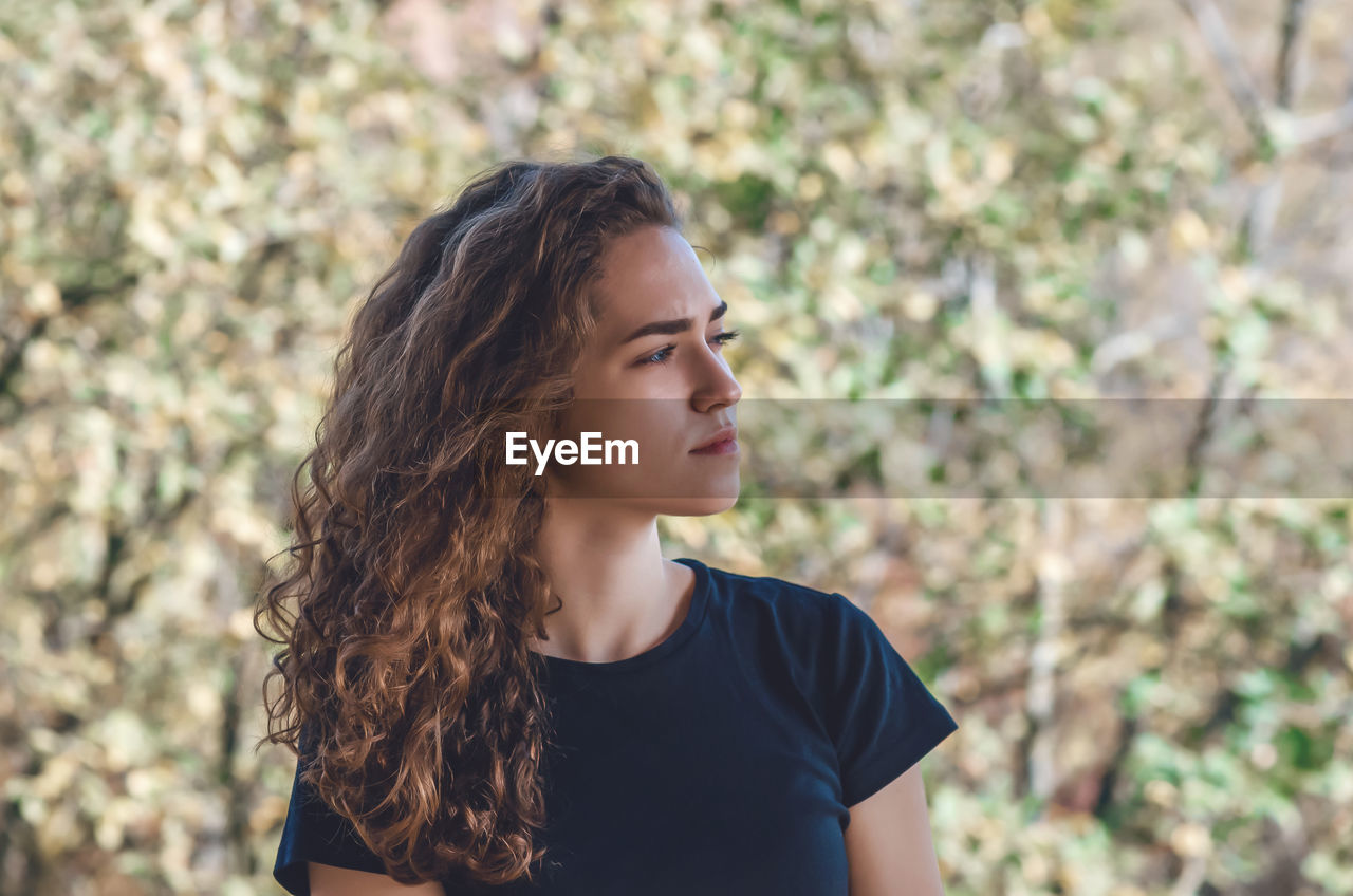 Face of woman dreaming with blue eyes outdoors. curly hair. autumn