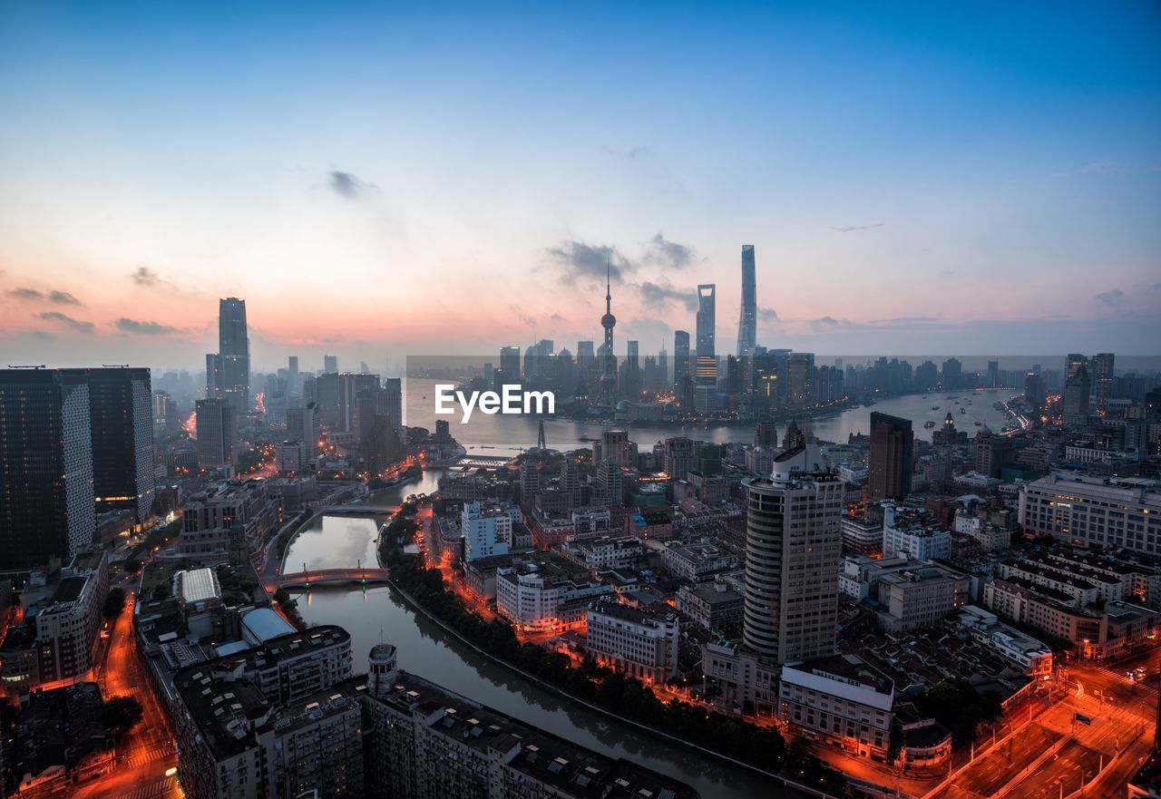 Aerial view of buildings in city against sky during sunset