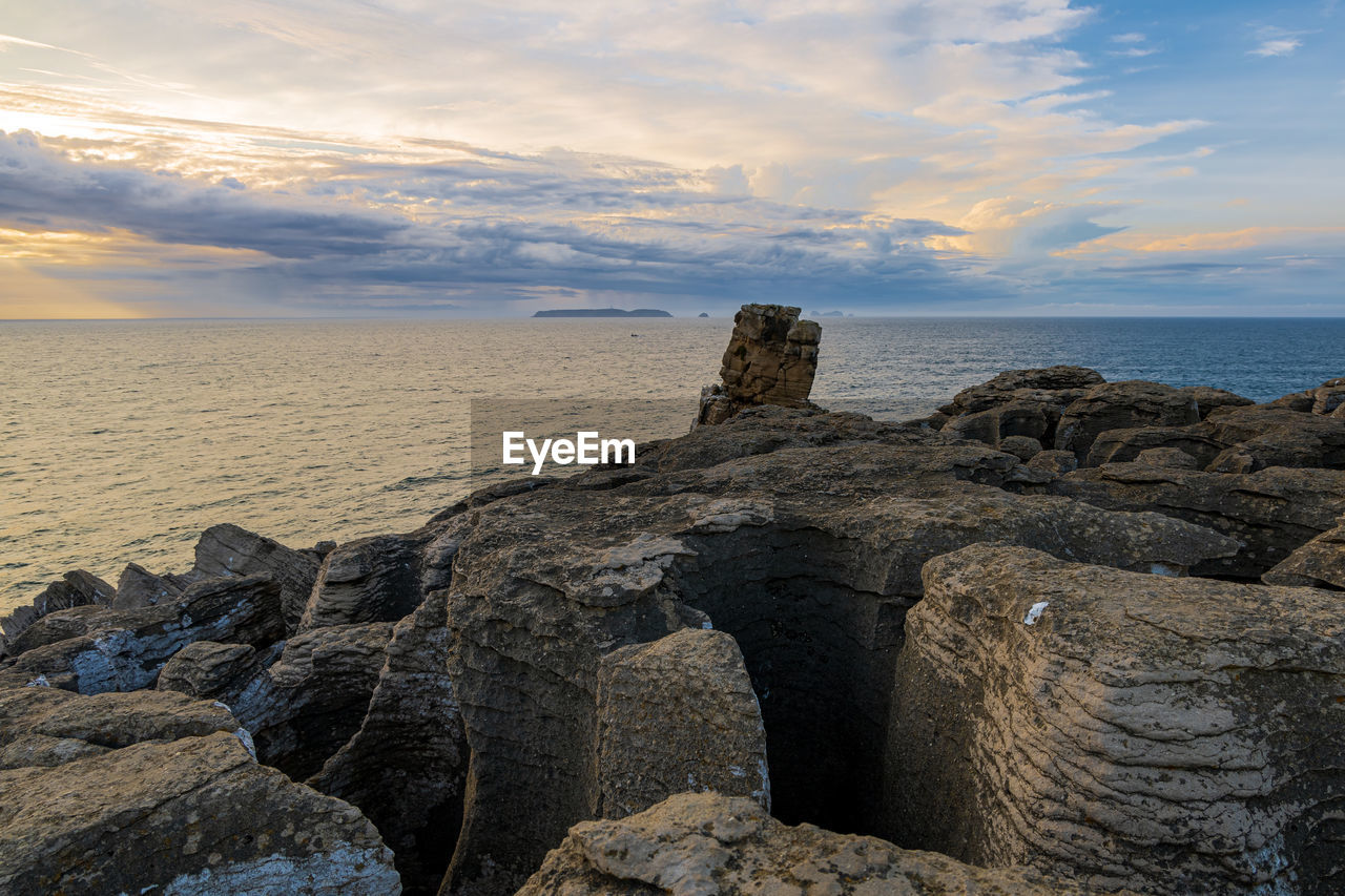 SCENIC VIEW OF ROCKS ON BEACH AGAINST SKY