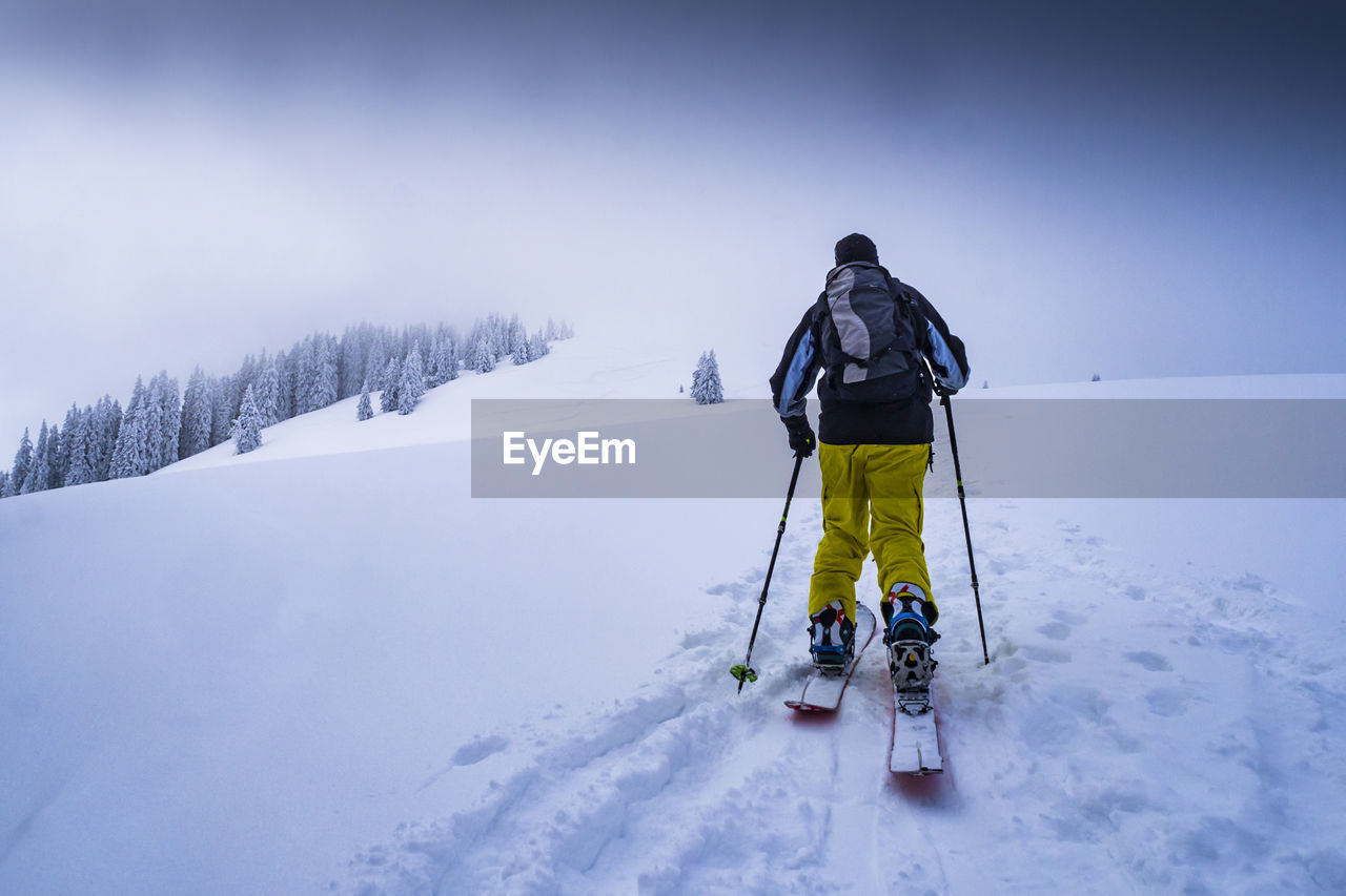 Rear view of man skiing on snow covered landscape