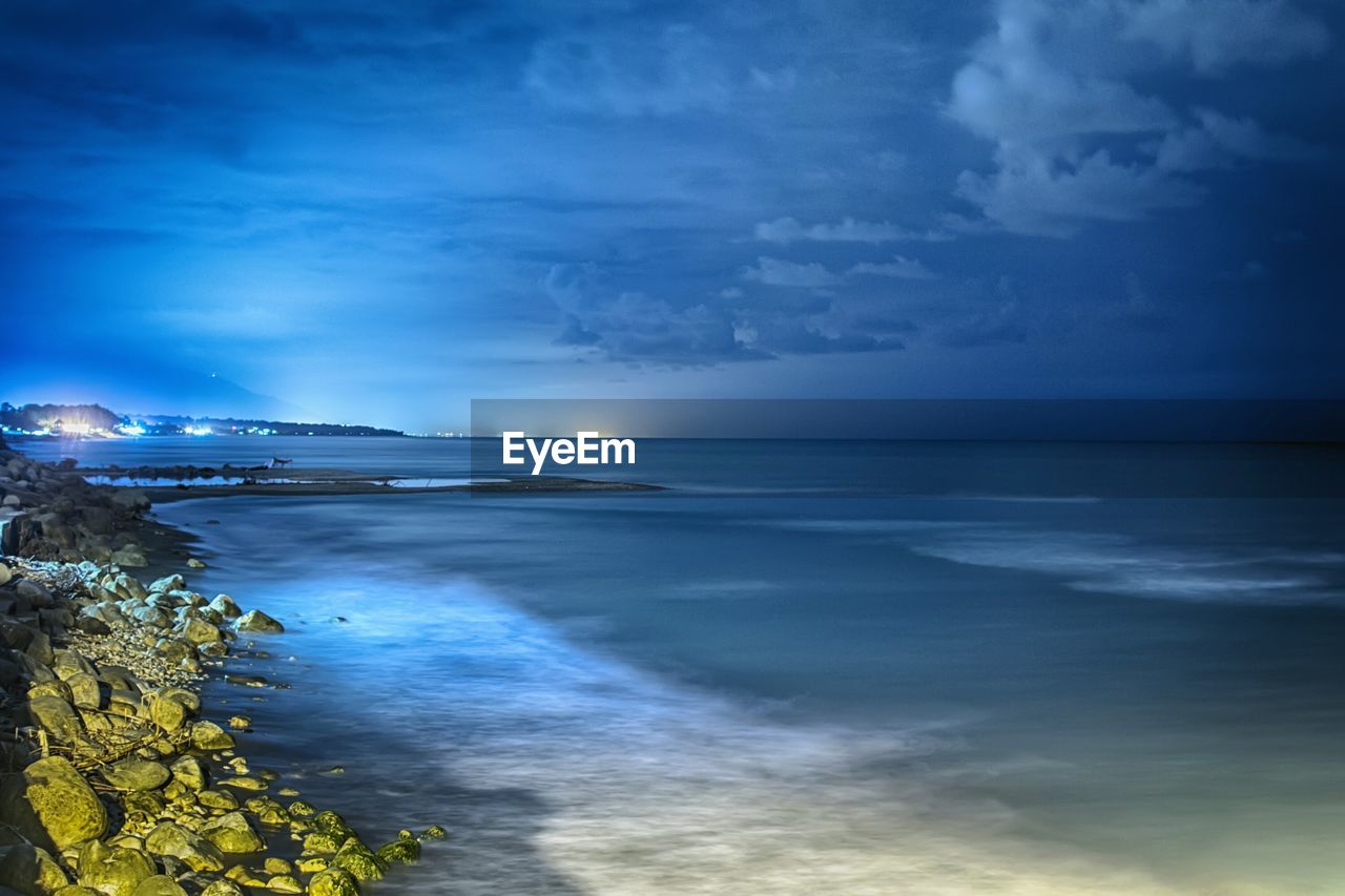 Scenic view of sea against cloudy sky at dusk