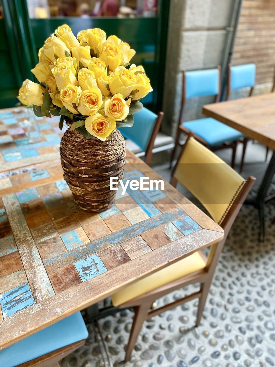 flower, flowering plant, table, yellow, seat, chair, plant, freshness, furniture, arrangement, no people, beauty in nature, nature, business, vase, indoors, flower arrangement, wood, food and drink, focus on foreground, bouquet, decoration, cafe, coffee table, container