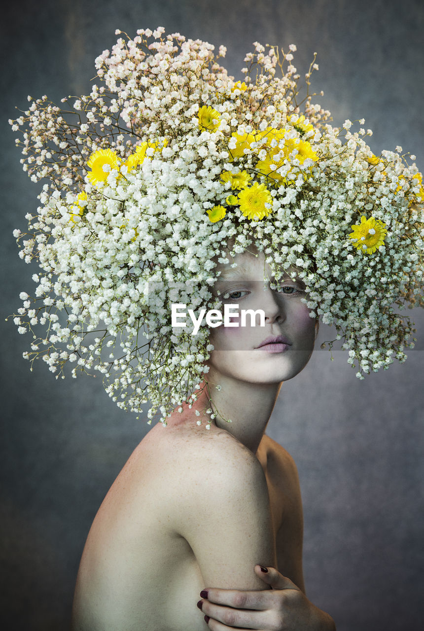 PORTRAIT OF SHIRTLESS YOUNG WOMAN WITH FLOWERS IN SUNLIGHT