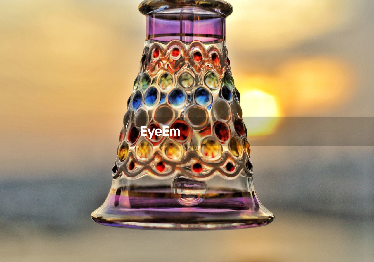 Close-up of multi colored glass bell with sunset over cityscape in background 