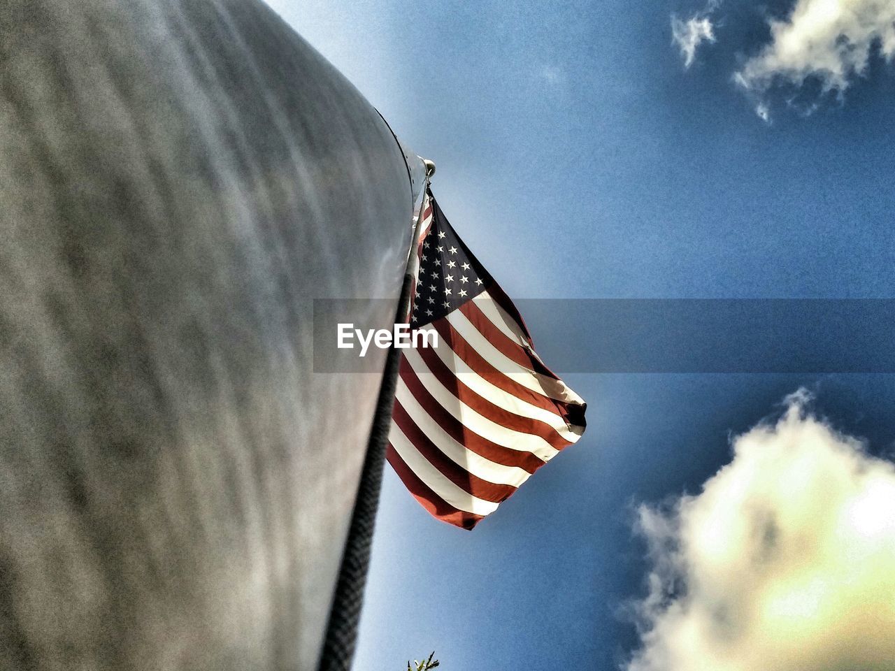 Directly below shot of american flag against cloudy sky