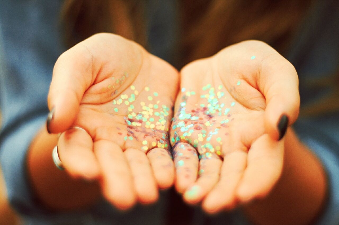 Midsection of woman showing hands with colorful confetti