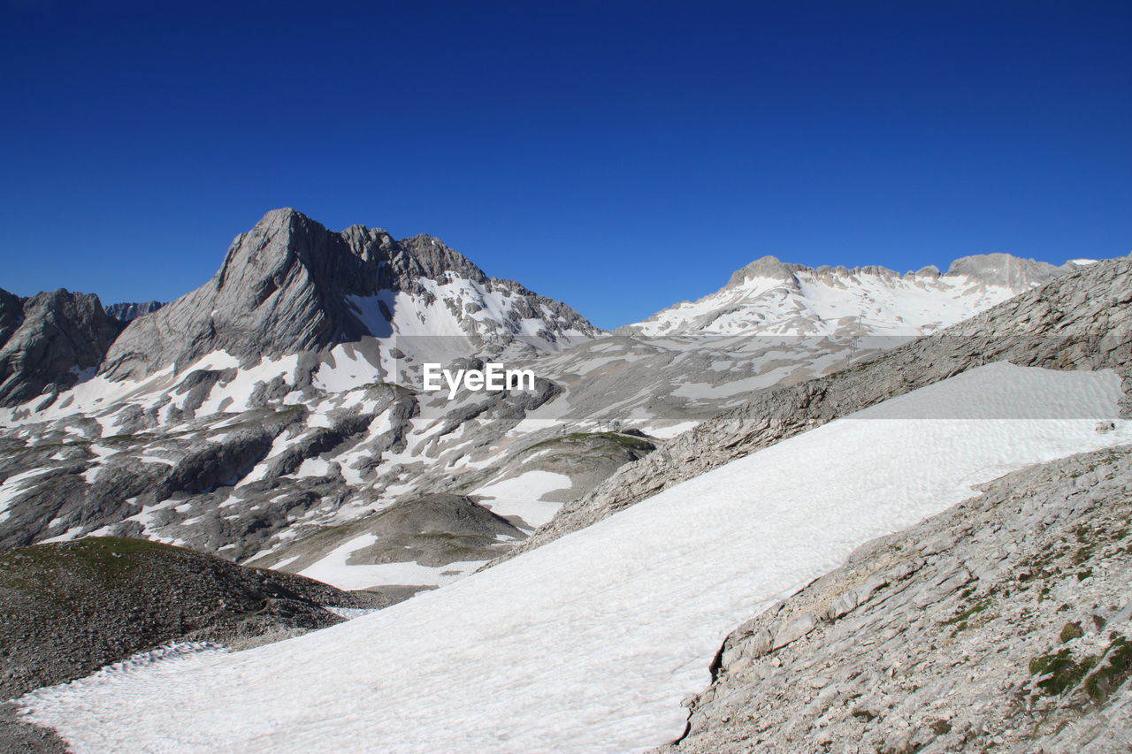 Scenic view of snowcapped mountains against clear blue sky