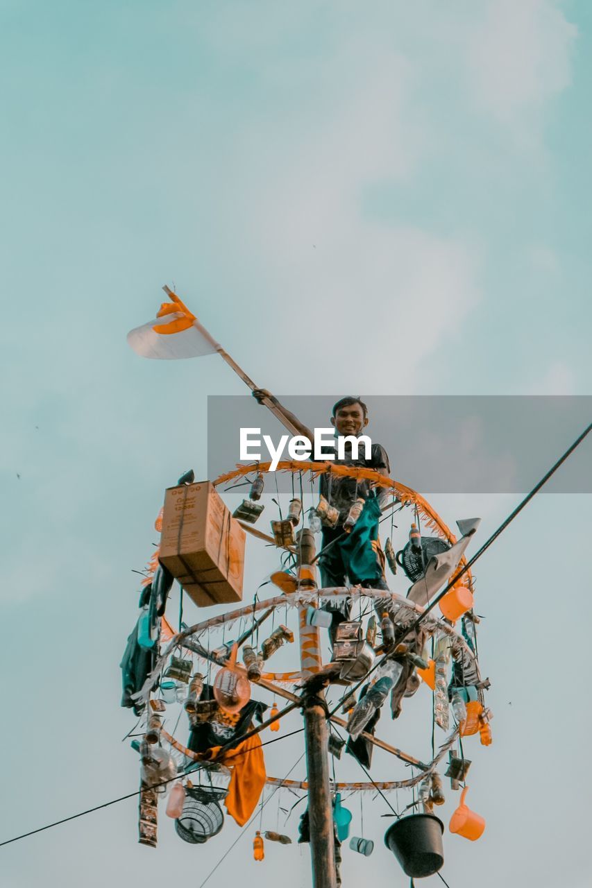 Low angle view of people on rope against sky