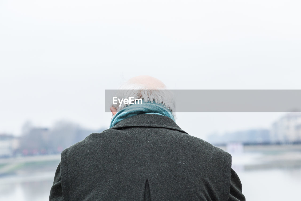 REAR VIEW OF MAN IN SNOW AGAINST SKY