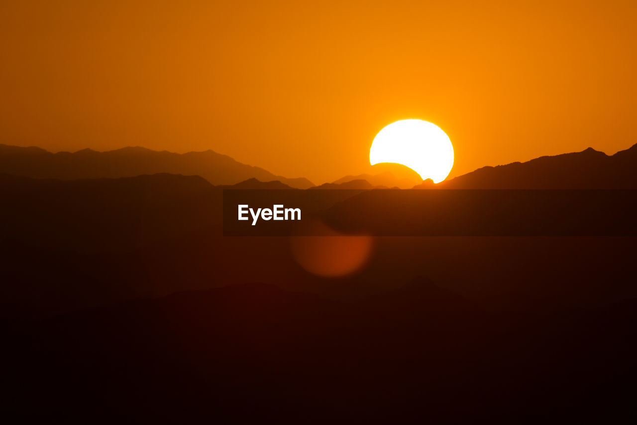SCENIC VIEW OF SILHOUETTE MOUNTAIN AGAINST ORANGE SKY