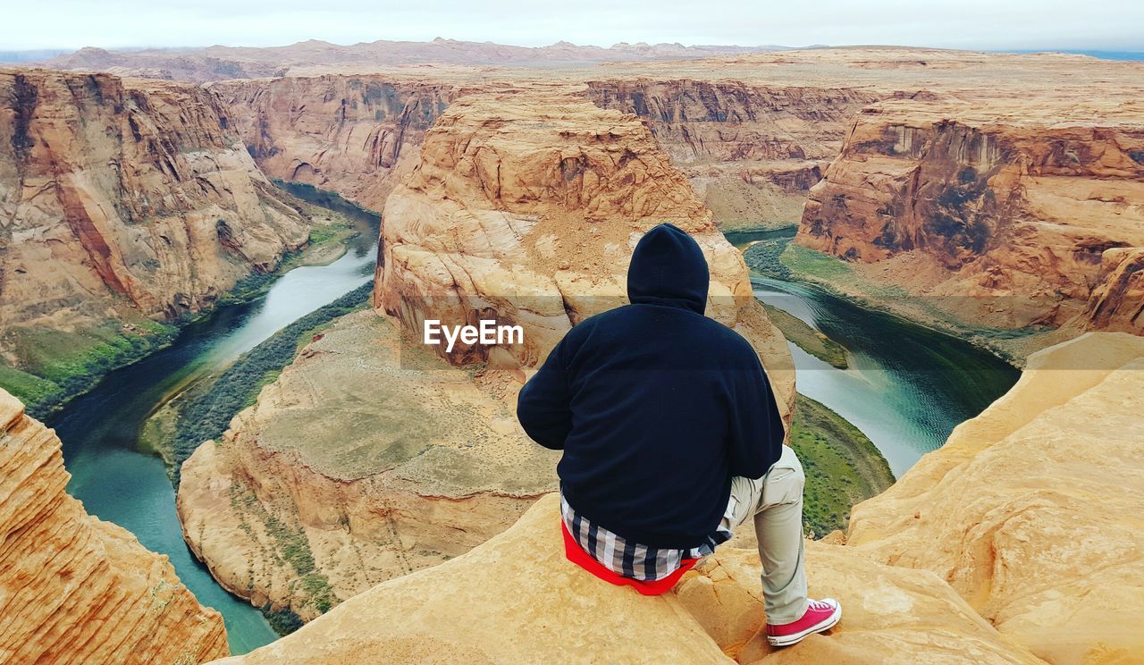 Scenic view of person sitting on rock against mountains