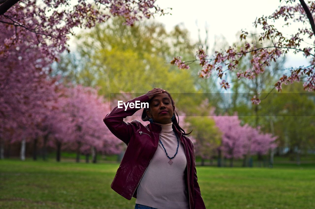 Young woman standing on field against trees
