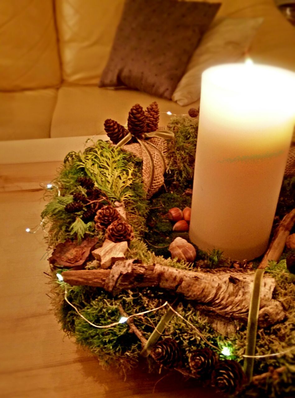 Advent wreath with lighted candle on table