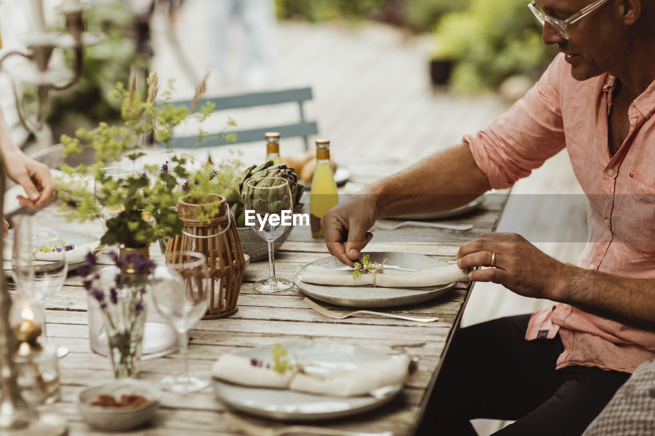 Mature man arranging plate on dining table