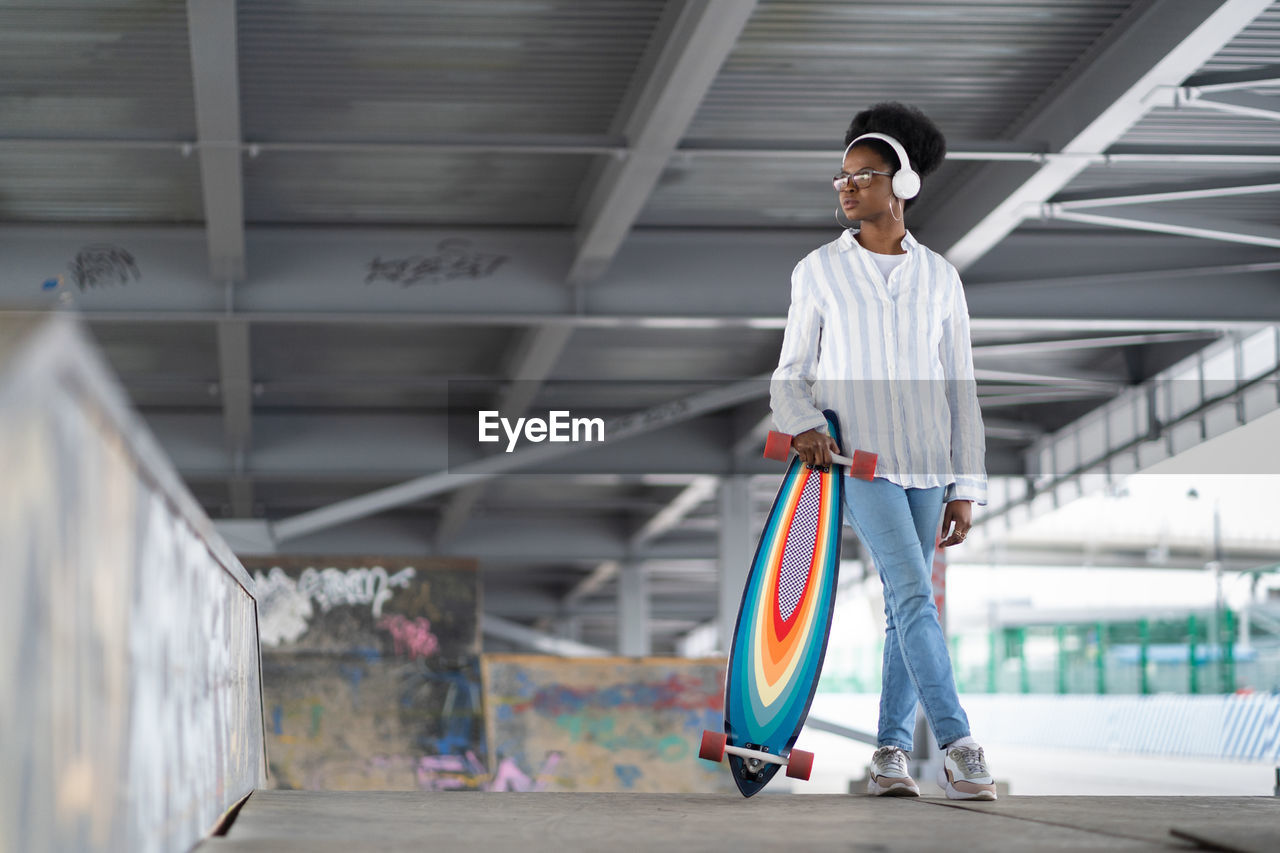 Full length of woman with skateboard standing outdoors