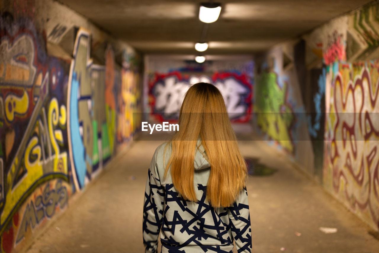 Rear view of woman standing against graffiti