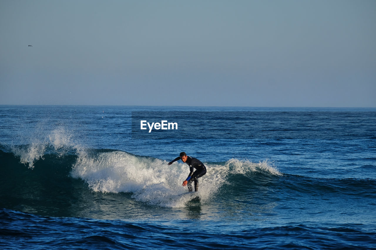 Man surfing on sea against clear sky