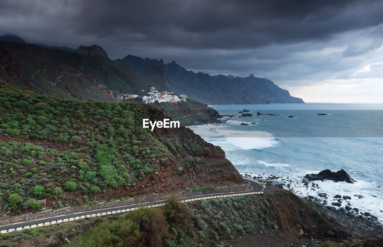 Scenic view of mountains by sea against cloudy sky