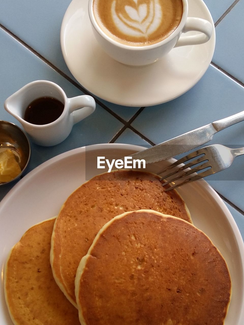 Breakfast with pancake and honey topping, accompany with a cup of cappucino