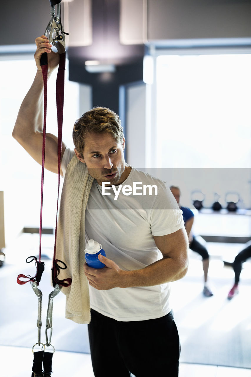 Tired man with towel and water bottle at health club