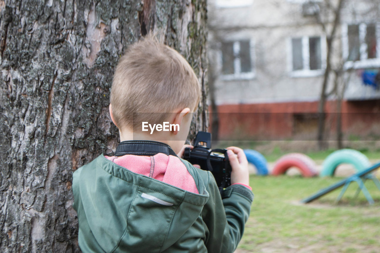 Kid on the street in a jacket with an film camera