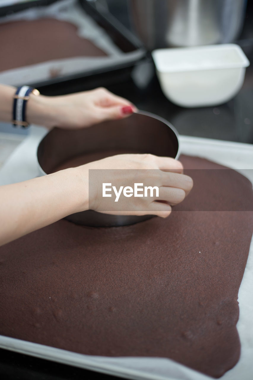 Cropped image of woman using pastry cutter over cake at kitchen