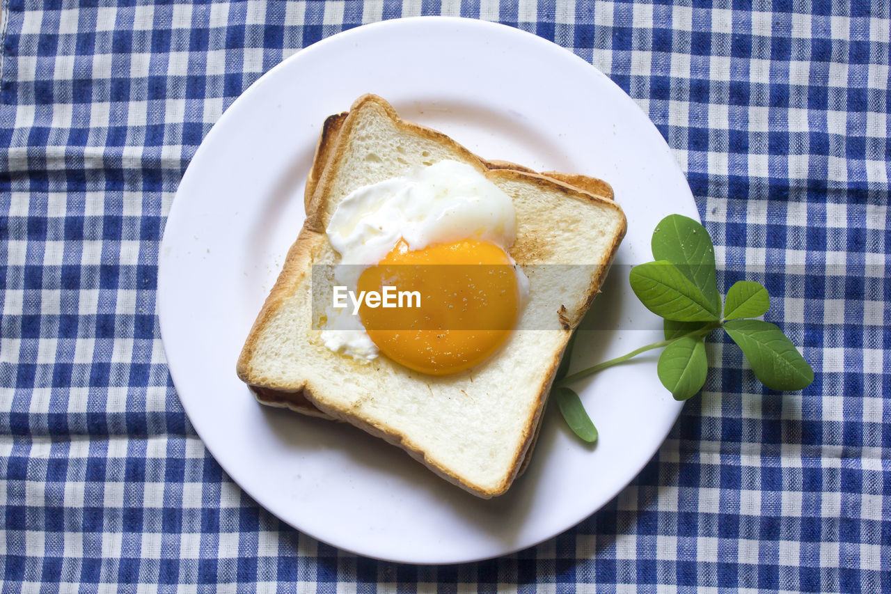 Fried egg on toast and black coffee in a glass.