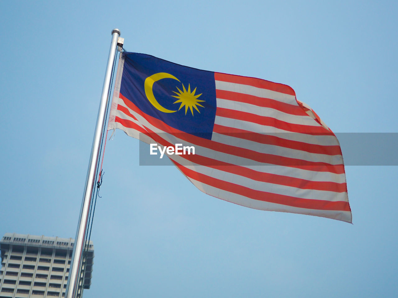 Low angle view of malaysian flag against blue sky