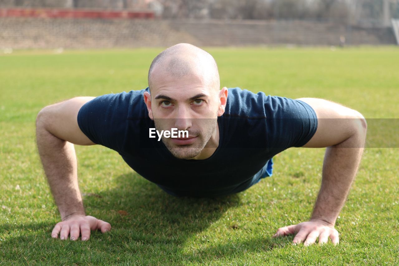 Portrait of man exercising on field