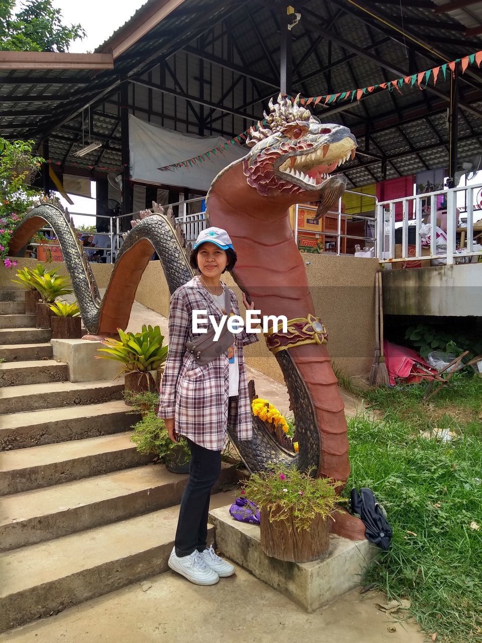 WOMAN STANDING BY POTTED PLANT ON STAIRCASE