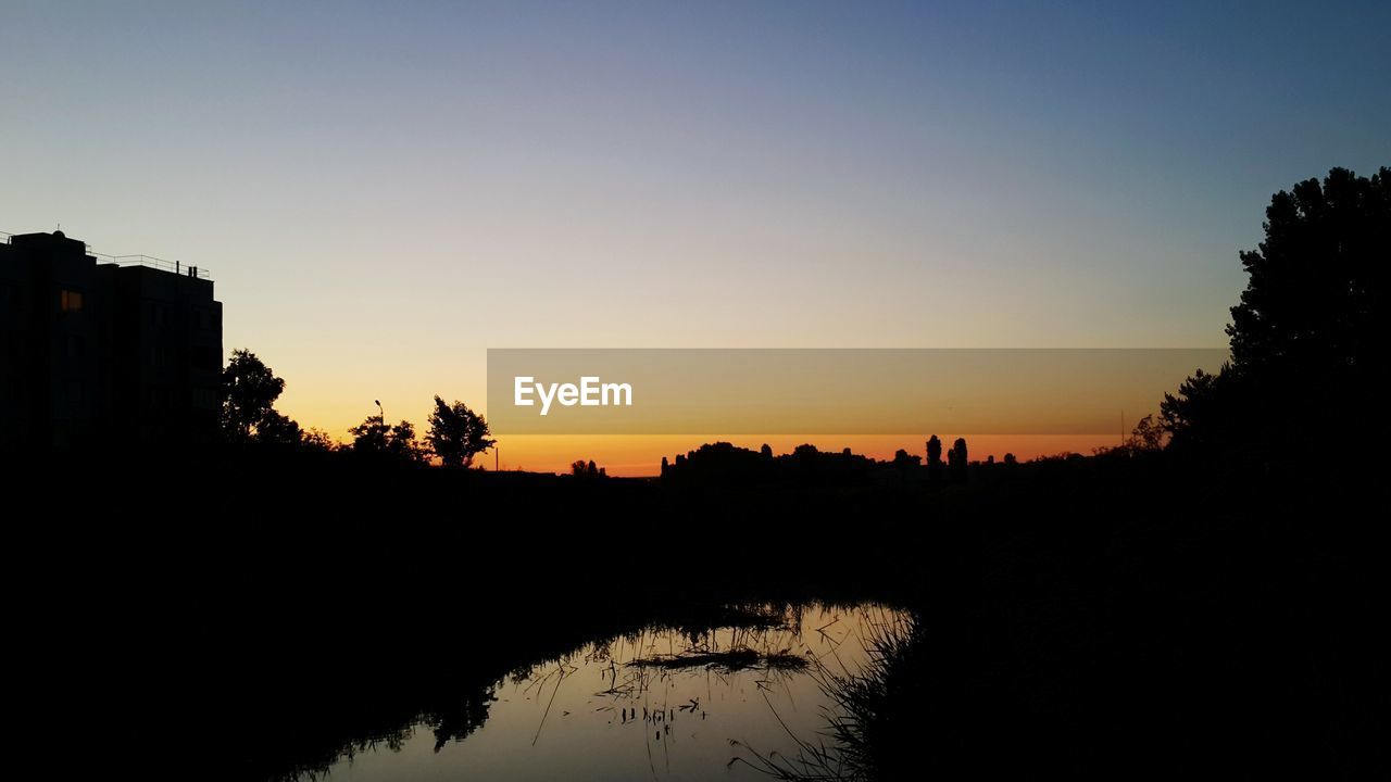 SCENIC VIEW OF LAKE AGAINST ORANGE SKY