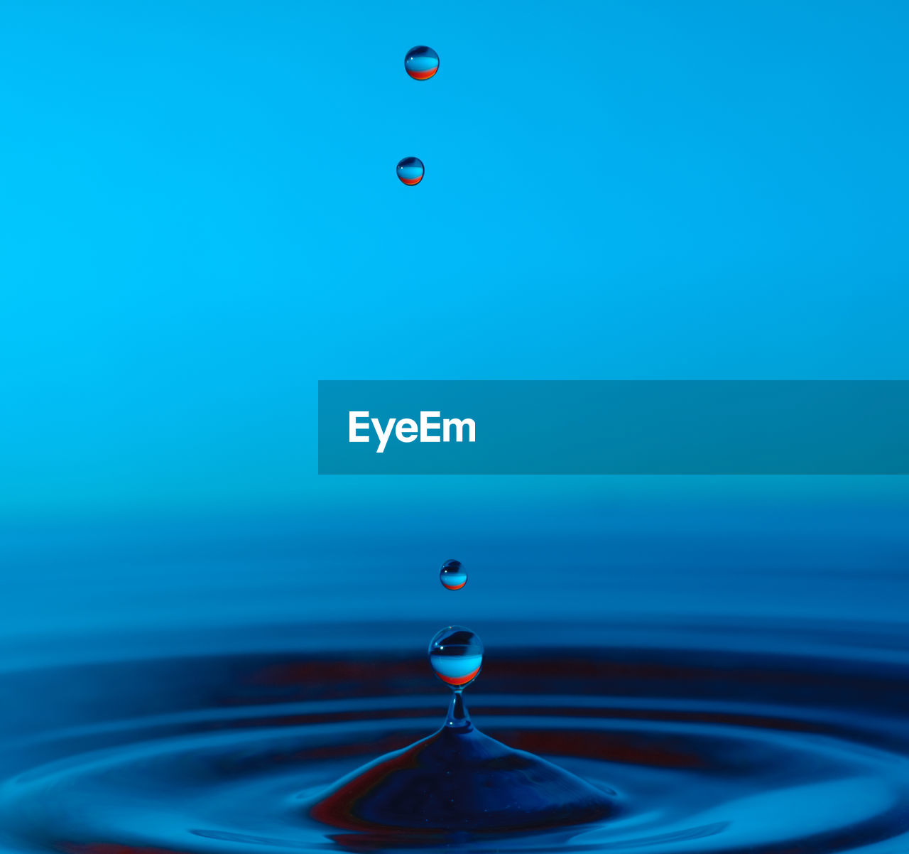 CLOSE-UP OF DROP FALLING IN BLUE WATER