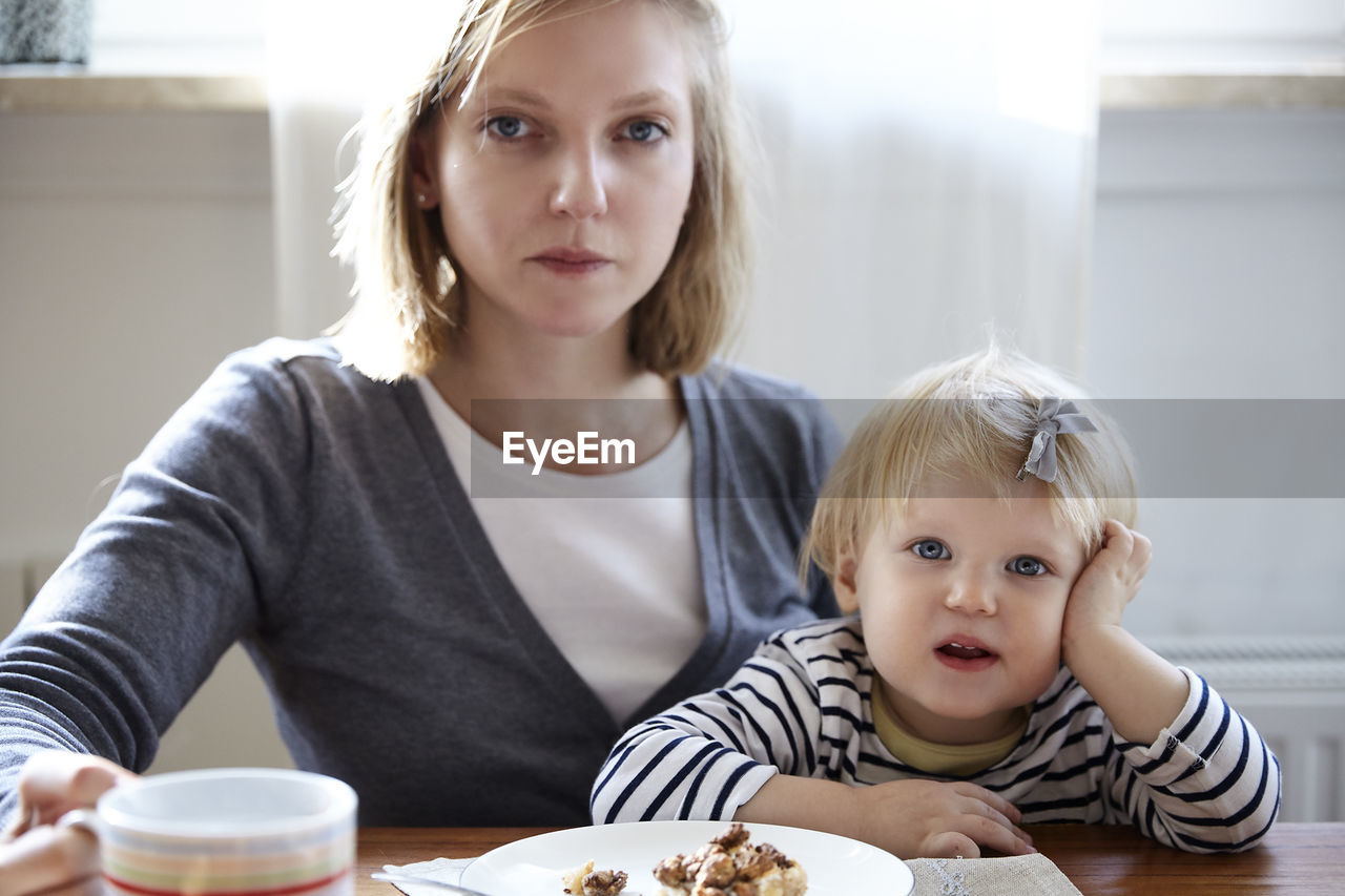 Portrait of mother and daughter having food at home