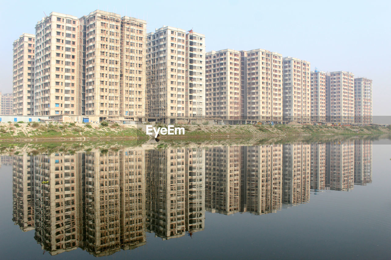 Reflection of residential buildings in lake against sky