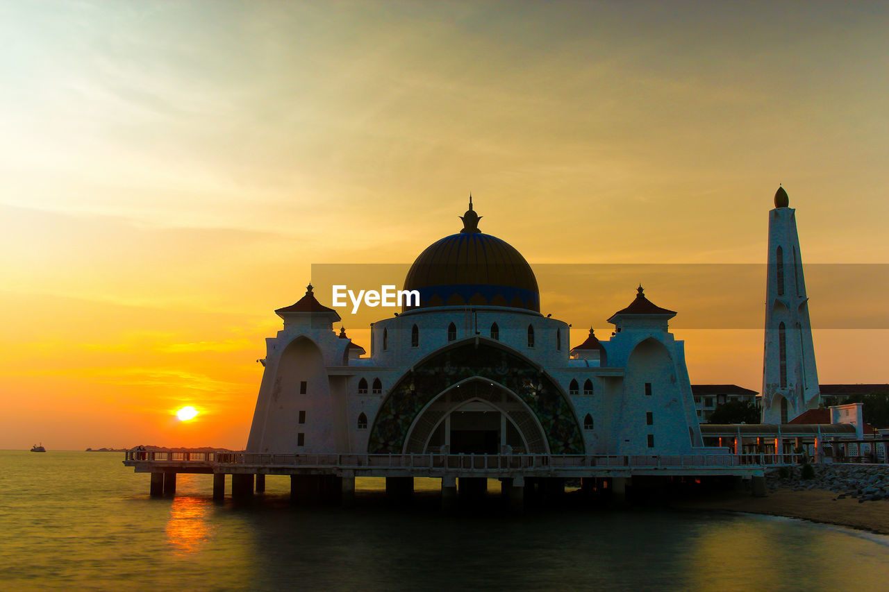 Malacca straits mosque by sea against sky during sunset