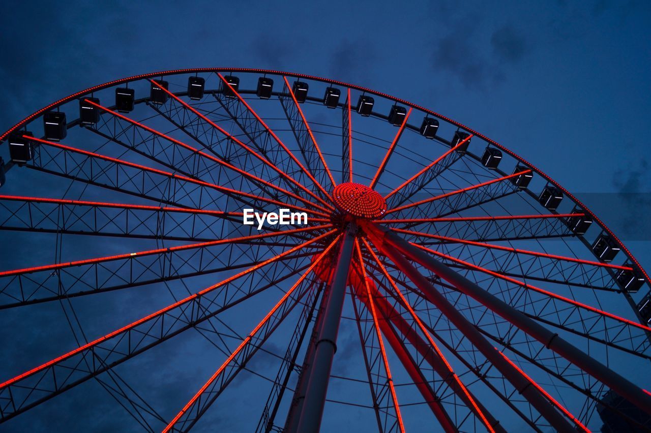 Low angle view of illuminated ferris wheel against sky at dusk