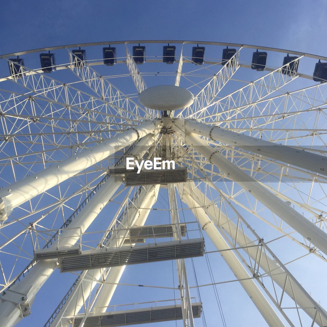 Low angle view of white ferris wheel at park against sky