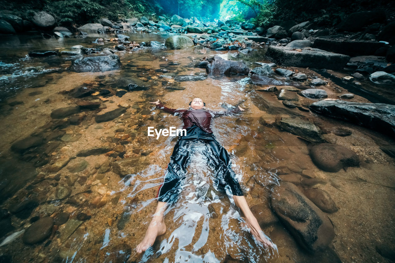 High angle view of boy lying in stream