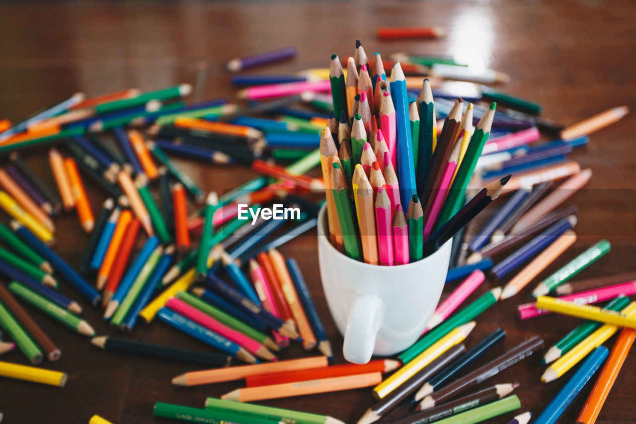 Close-up of multi colored pencils in cup on table