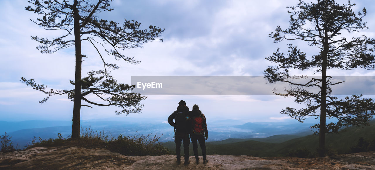 rear view of man standing on mountain against sky