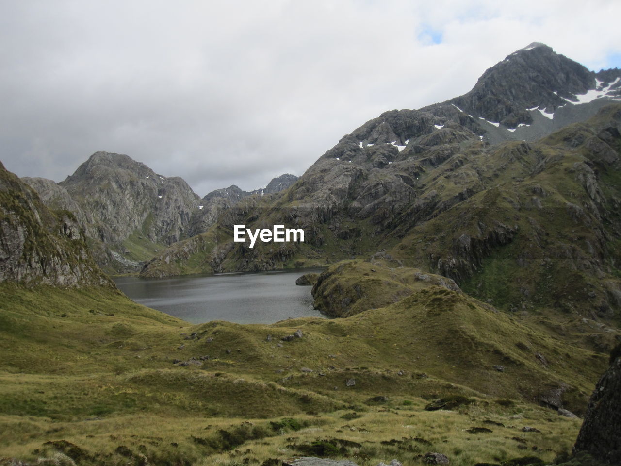 Scenic view of mountains and lake against cloudy sky