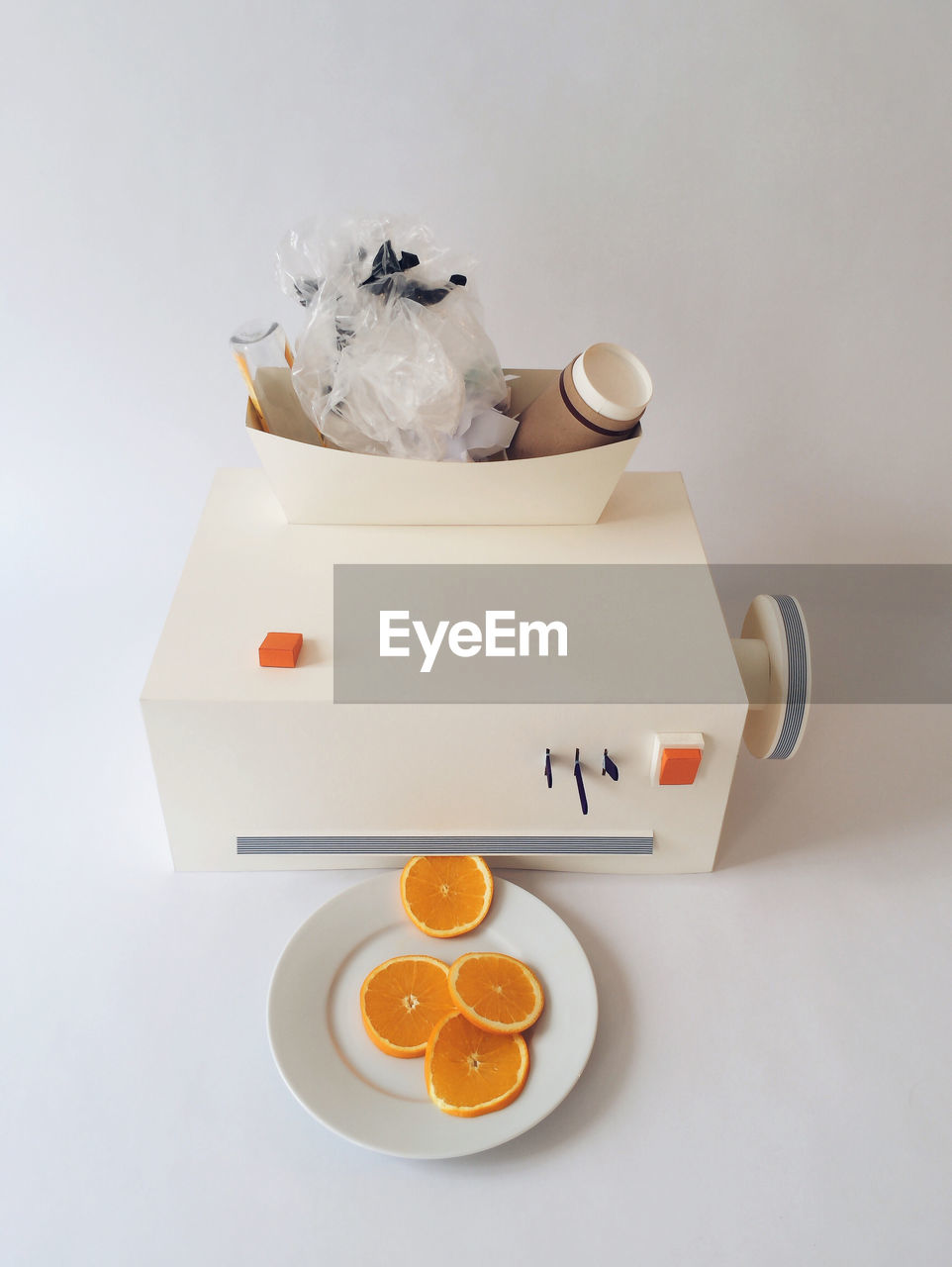 High angle view of orange slices in plate with machinery on white background