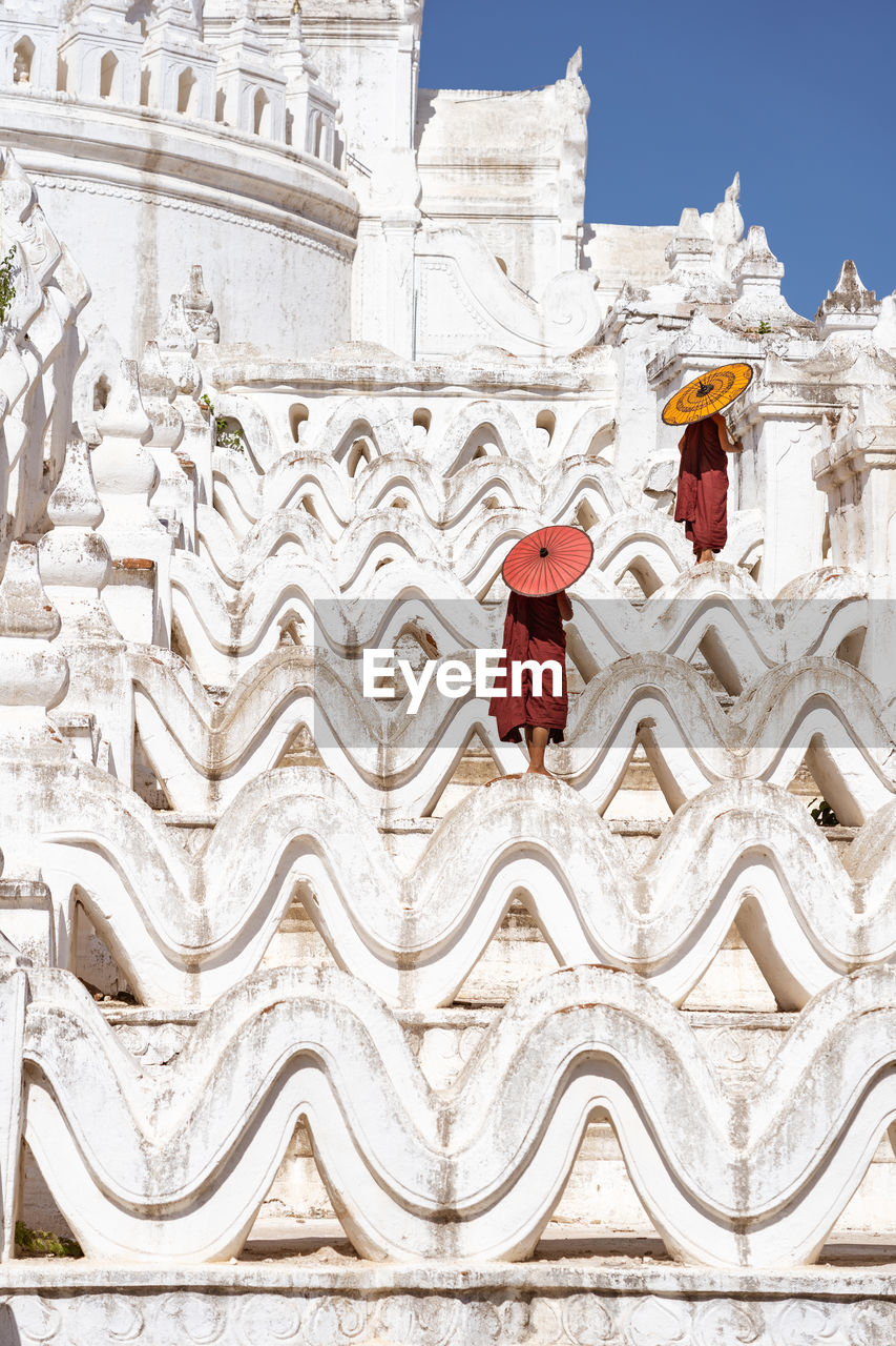 Monks with umbrellas standing on temple